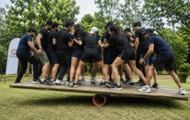 Corporate team helping one another through a rope web outdoors